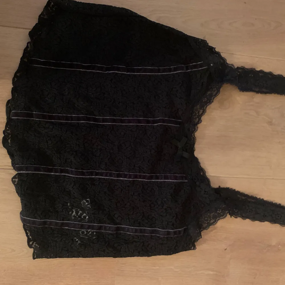 Svart spetstop med sammet detaljer och en rosett. Köpt i Australien och aldrig använd. Storlek M men passar andra storlekar också. Jätte snygg över att vit linne eller med bara en BH under. Yläosat.
