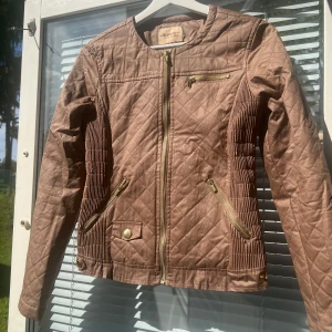 Jacka- Hypnotic - En fin höst jacka, guldiga detaljer samt fickor, färgen är brun, har använts några gånger men är i bra skick och har inga skador eller fläckar, modellen är tajt men annars normal i storleken, storlek S, inuti är den väldigt fin randigt ljusblå. 