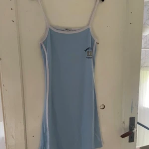 Ljusblå klänning från Wang - Säljer en superfin ljusblå klänning från Wang i storlek XL. Den har smala axelband och en sportig look med vit kant. Perfekt för en avslappnad sommardag eller en dag på stranden!