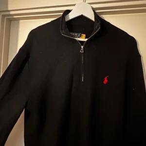 Svart tröja från Ralph Lauren - (NYSKICK) En stilren svart tröja från Ralph Lauren. Den har en dragkedja, klassiska loggan. Tröjan är tillverkad i kammad bomull för en mjuk och bekväm känsla. Perfekt för  vardag och lite finare tillfällen. Nypris 1200kr, kan mötas upp i Värmland!