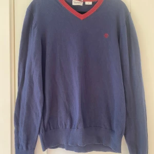 Marinblå v-ringad tröja från Timberland i strl S - Marinblå v-ringad tröja från Timberland i strl S.  Använd, lite små nopper i övrigt i bra begagnat skick.  Mått Över bröstet: ca 52 cm Längd från axeln och ner: ca 63 cm  54% bomull, 34% nylon, 10% ull och 2% elastan 