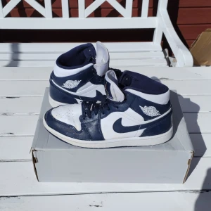 Nike Air Jordan 1 Mid White/Blue 554724-174 - Säljer ett par begagnade Air Jordan 1 Mids i utmärkt skick!  Kommer med en Air Force box och alltså ej orginalboxen.