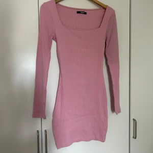 Rosa ribbad klänning från Bik Bok - Säljer en superfin rosa ribbad klänning från Bik Bok. Den har en fyrkantig urringning och långa ärmar, perfekt för både vardag och fest. Klänningen är i storlek S och sitter riktigt snyggt på kroppen. Passar perfekt till vår och sommar!