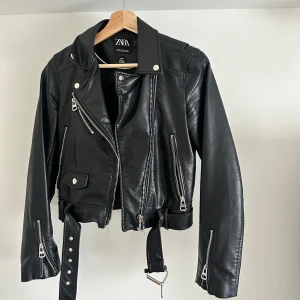 Skinnjacka Zara - En gammal klassiker från Zara, Skinnjacka med många dragkedjor. Jackan är använd men i extremt bra skick. Silverdragkedjan på vänstra bröstet har rostat lite men inget som är synligt. Passar både XS och S!💕 kontakta för fler bilder💕💕