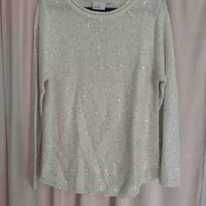 Beige glittrig tröja från Isolde - Säljer en superfin varmvit tröja från Isolde. Den är stickad och har ett glittrigt mönster. Tröjan har långa ärmar och en rund halsringning. Lappen med storleken är borta men det är en L. 