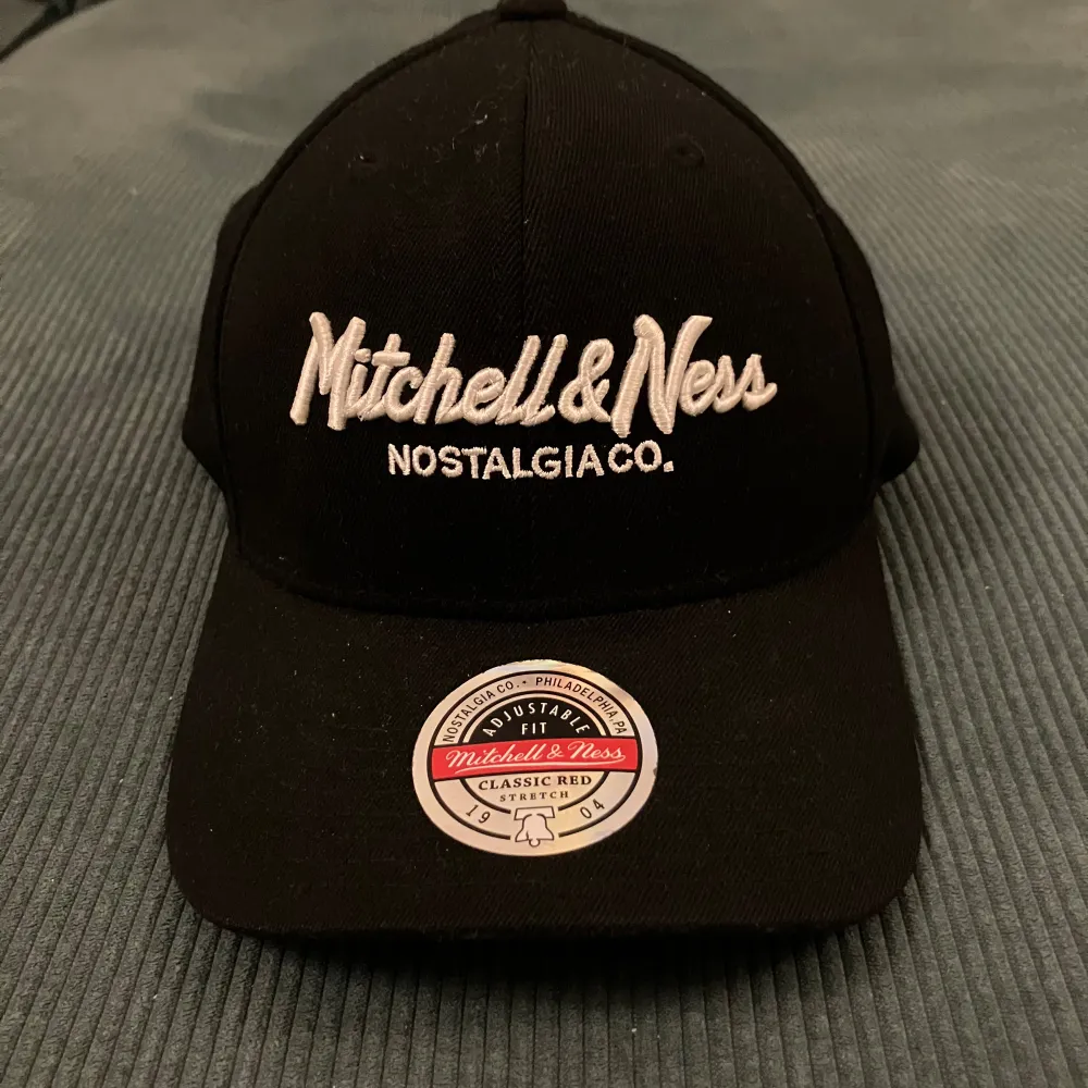 Säljer en snygg svart keps från Mitchell & Ness med broderad logga både fram och bak. Kepsen har en klassisk design med justerbar rem baktill för perfekt passform. Perfekt för vardagsbruk eller som en stilren accessoar.. Accessoarer.