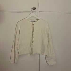 Vit tröja med knyt från Gina Tricot - Säljer en stilren vit tröja från Gina Tricot med knyt framtill. Tröjan har långa ärmar och en enkel design som passar perfekt till olika tillfällen.  Perfekt för dig som gillar en minimalistisk stil. Nyskick, enbart testad❣️