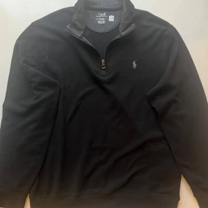Polo Ralph Lauren Half Zip - Svart - Tröja från Polo Ralph Lauren med en halv dragkedja framtill och det klassiska logotypbroderiet på bröstet. 