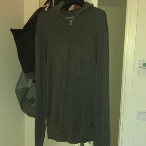 Grå tröja med dragkedja - Säljer en stilren grå tröja med dragkedja vid halsen. Tröjan har långa ärmar och är perfekt för en avslappnad look. Passar bra till både jeans och chinos. Från Jack & jones. Stor i storleken sol ni ser på bilden så den passar storlek M också. 