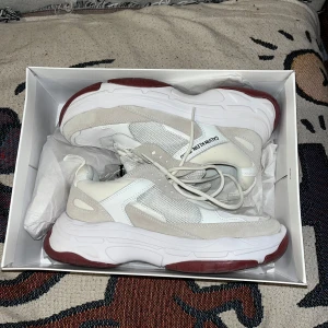 Vita sneakers från Calvin Klein Jeans - Snygga vita sneakers från Calvin Klein Jeans med en chunky sula i röd och vit. Skorna har snörning och detaljer i mocka och syntet. Perfekta för en trendig look.