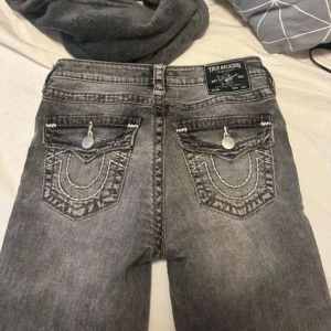 Grå jeans från True Religion - Snygga grå bootcutjeans från True Religion med unika broderade detaljer på bakfickorna. Köpta för 1900 på raglady. Knappt använda 