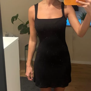 Svart tight klänning - Snygg svart tight klänning med ärmlös design och öppen rygg. Perfekt för en kväll ute eller en speciell tillställning. Klänningen har en elegant och stilren look.