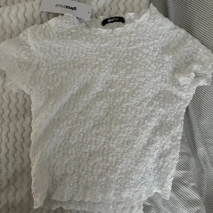 Vit ribbad topp från Gina Tricot - Säljer en söt vit topp från Gina Tricot. Toppen är kortärmad och har en elastisk struktur som ger en fin passform. Perfekt för varma dagar!Använd ungefär 2 gånger💕💕