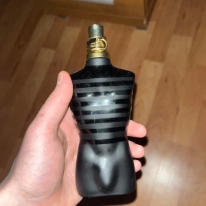 Jean Paul Gaultier Le Male Le Parfum 125ML - Säljer en flaska Jean Paul Gaultier Le Male Le Parfum, en intensiv och maskulin doft. Flaskan är formad som en manlig torso i svart med guldiga detaljer. Förpackningen är en elegant svart burk med guldtext. Perfekt för den som vill ha en kraftfull och sofistikerad doft.110ML kvar!