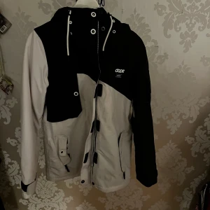 Svart och vit jacka från Dope - Säljer en stilren svart och vit jacka från Dope. Det finns tecken på användning då den är lite smutsig men de går bort i tvätt.