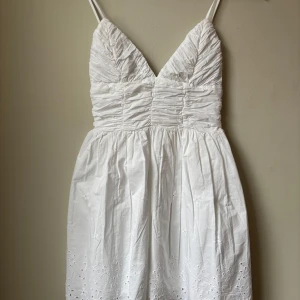 Vit klänning från Zara - Säljer en söt vit klänning från Zara med smala axelband och v-ringad design. Klänningen har en rynkad överdel och broderade detaljer på kjolen. Perfekt för sommaren eller för någon som tar studenten!🩷Klänningen är endast provad men var alldeles för liten för mig tyvärr.