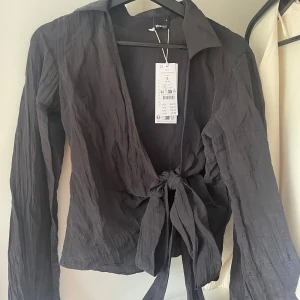 Blus - En svart blus från Gina tricot med knytning, aldrig använd och med prislapp kvar!!💕