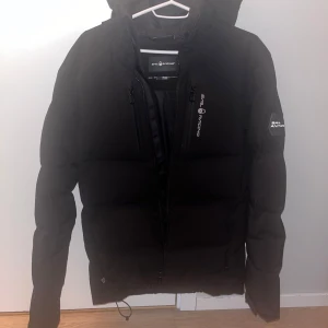 Sail Racing vinterjacka - En snygg sail racing vinterjacka. Har inte använt den på två år, men fortfarande i gott skick endast en nackdel är defekten på ryggen.  Nypris: 4500 kr