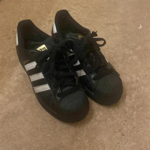 Adidas superstar - Säljer mina jättefina adidas superstar då dom tyvärr är för små för mig. Storlek 36 och i hyfsat bra skick. Några defekter, skriv för närmare bilder på dom. Köpta på stadsmissionen nästan helt oanvända. Skosnörerna lite trasiga men skickas med ändå🩷