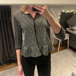 Grå kofta - Grå skön kofta med knappar med en volang neråt