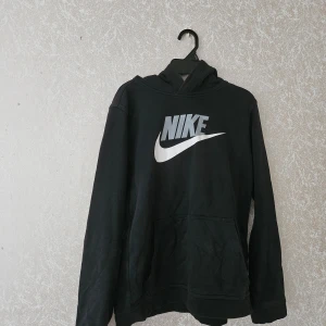 Nike svart huvtröja - Svart huvtröja med stor vit Nike-logotyp på framsidan. Huvan är fodrad med mjukt tyg.