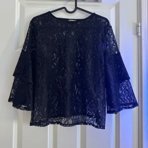 Svart spetsblus med trekvartsärm - Säljer en elegant svart spetsblus med trekvartsärm. Blusen har en lös passform och är perfekt för både fest och vardag.🤩