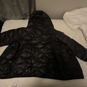Svart pufferjacka med huva - Säljer en svart pek performance jacka som är perfekt för kalla dagar. Jackan har en mysig huva och quiltad design som håller dig varm. Den är använd 3 gånger och är i perfekt skick. Priset går att diskutera vid snabb affär 