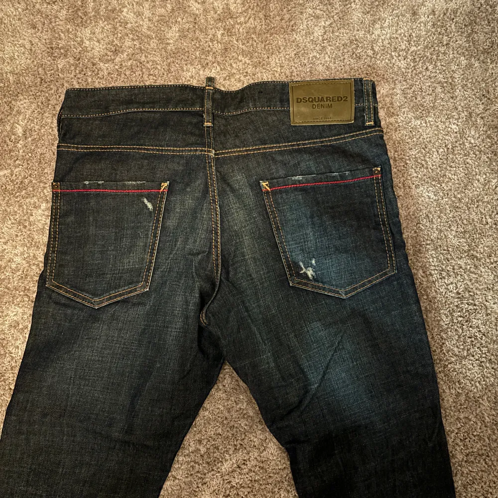 Snygga jeans från Dsquared2 med en slim fit. De har en mörkblå färg och en distinkt stil. Jeansen har inga deffekter och har inte använts mycket alls,   Måtten är:   Midjevidd: 45 cm  Yttre benlängd: 110 cm   Inre benlängd: cirka 83 cm. Jeans & Byxor.