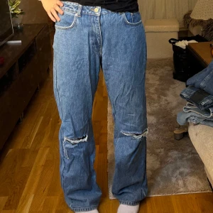 Blå jeans med slitningar - Säljer ett par snygga blå jeans med slitningar på knäna. De har en klassisk femficksdesign och är i en straight fit. 💕