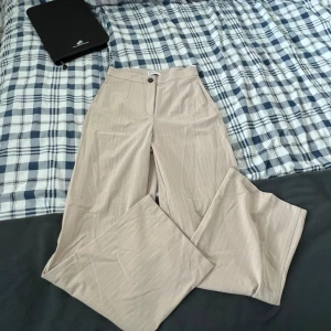 Kostymbyxa beige - Beiga kostymbyxor från bershka, oanvända!  Mönster: små vita ränder 