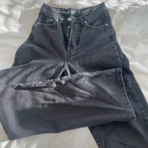 Svarta jeans med regular fit - Säljer ett par svarta jeans i regular fit. De har en klassisk design med fem fickor och knappgylf. Perfekta för vardagsbruk och kan enkelt matchas med olika toppar. Storlek 25 i midjan och längd 32. Endast testade!