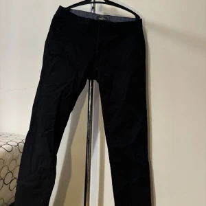 Svarta byxor från Dressmann - Säljer ett par svarta byxor från Dressmann i storlek 31/30. De har en slim fit passform och är perfekta för en stilren look. Byxorna är i bra skick och passar både till vardags och festligare tillfällen. Nypris: 499