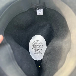 Svart hatt från Lock & Co. Hatters - Säljer en stilren svart hatt från Lock & Co. Hand gjort precis som alla deras hattar, om du vill ha en kvalitativ hatt som kommer håll hela livet ska man ha en från lock & co .Hatten är i storlek 59 L .  Priset kan diskuteras vid snabb affär.