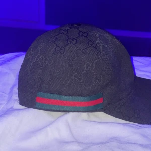 Gucci keps  - Hej säljer min Gucci keps då jag har tröttnat på färgen har klippt bort lappen då de kliades och den åkte ut hela tiden jag fraktar och jag möts bor i grästorp hör av er om ni vill ha mer info osv 