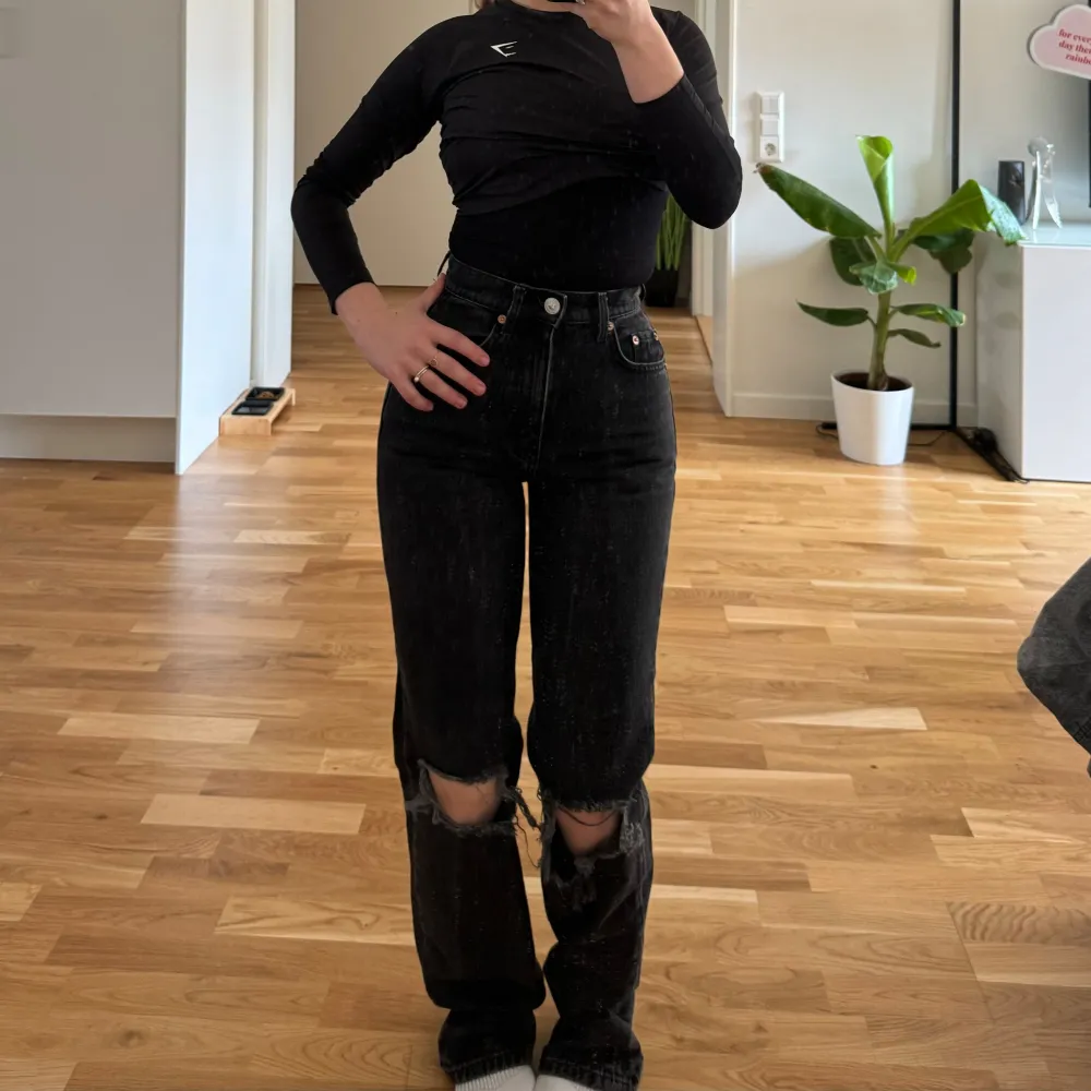 Säljer ett par svarta jeans med coola slitningar på knäna. De är högmidjade och har en straight passform som ger en avslappnad look. Perfekta för en casual outfit eller när du vill lägga till lite edge till din stil. De är i bra skick och redo för nya äventyr!. Farkut & Housut.