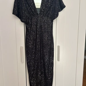 Svart festklänning  - Tjusig festklänning för äldre damer✨ klänningen täcker axlarna och är lite öppen. Den går också hela vägen ner till golvet.   du kanske vill uppgradera din garderob med något fint och glittrigt till nyår?🥳 Helt ny och oanvänd- etikett på