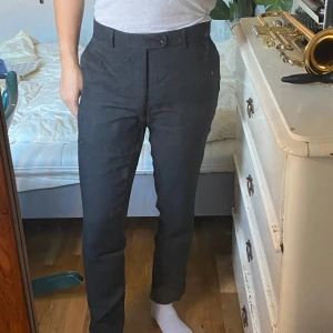 Grå kostymbyxor - Säljer ett par stiliga mörkgrå kostymbyxor i ett diskret rutmönster från bläck. De är midwaist och har en straight passform som ger en klassisk look. 