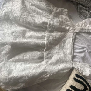 Vit klänning med blommigt mönster - Säljer en superfin vit klänning med ett vackert blommigt mönster. Klänningen har en elegant design med detaljer som ger en romantisk känsla. Perfekt för sommarens alla fester eller en mysig midsommarfirande. Materialet känns lätt och luftigt, vilket gör den idealisk för varma dagar.