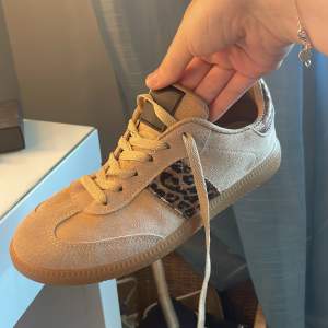 Säljer ett par snygga beige sneakers från Marquitz. De har coola leopardmönstrade detaljer på sidorna och en bekväm snörning. Skorna är i mocka och har en normal passform. Perfekta för både vardag och fest!