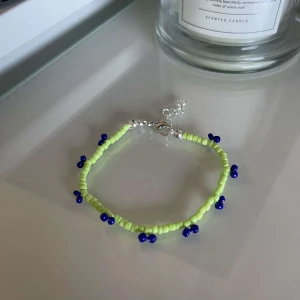 Grönt och blått pärlarmband - Säljer ett superfint armband med gröna och blå pärlor. Armbandet har en justerbar kedja och är perfekt för att ge lite färg till din outfit. Passar både till vardags och fest!