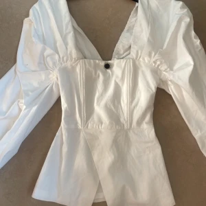 Elegant blus  - Elegant blus med stora ärmar och smal passform i storlek XS från Asos Luxe. Ditsydd knapp.