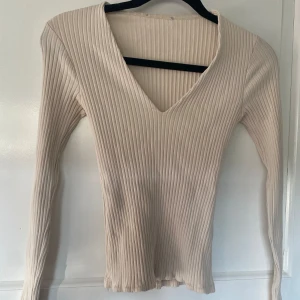 Tröja - Säljer en snygg beige ribbad tröja med v-ringning🤎Det finns en liten fläck på framsidan, men annars i bra skick!!