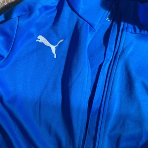 Blå Puma Kofta - Blå Puma kofta, använd några gånger, i väldigt bra skick, har två fickor (insidan och utsidan), lite stor i storleken men den är storlek S
