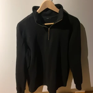 Svart tröja med dragkedja från Aveny - Säljer en stilren svart tröja från Aveny i storlek M. Tröjan har en praktisk dragkedja vid halsen och är perfekt för både vardag och lite kyligare dagar. Den är i bra skick och passar till det mesta i garderoben.