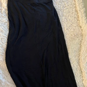 Svart långkjol från Nelly - Säljer en elegant svart långkjol från Nelly i storlek XS. Kjolen är perfekt för både vardag och fest och har en skön passform. Den är gjord i ett mjukt material som faller fint. Stretchig så passar även den som har storlek M.