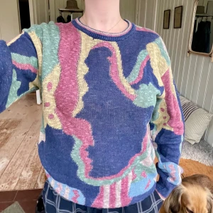 Färgglad stickad tröja - Säljer en supercool och färgglad stickad tröja med abstrakt mönster i blått, rosa, grönt och gult. Tröjan har en normal passform och långa ärmar, perfekt för att liva upp garderoben. Den är i bra skick och redo för nya äventyr!