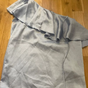 Fin blå blus med volang  - Så fin blå blus med volang som går snett över ena axeln. Kommer inte till användning men är så fin🥰passar S-L