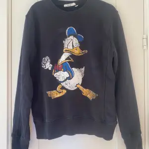 Svart sweatshirt med Kalle Anka Disney signature från Emilio i strl S.  Använd men i fint begagnat skick.  Mått Över bröstet: ca 51 cm Längd från axeln och ner: ca 63 cm  100% bomull   Kommer från ett djur och rökfritt hem.