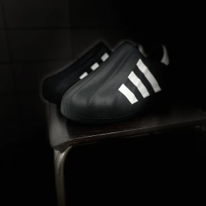 Svarta sneakers från Adidas - Säljer ett par svarta sneakers från Adidas med de klassiska tre vita ränderna på sidan. Skorna har en modern och stilren design, perfekt för både vardag och träning. De är i nyskick och redo att användas direkt. Passar perfekt för dig som gillar en sportig och minimalistisk stil.