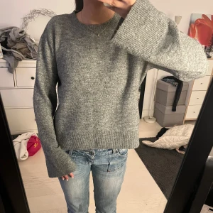Grå stickad tröja - Mysig grå stickad tröja med långa ärmar och ribbade muddar. Perfekt nu till vintern.